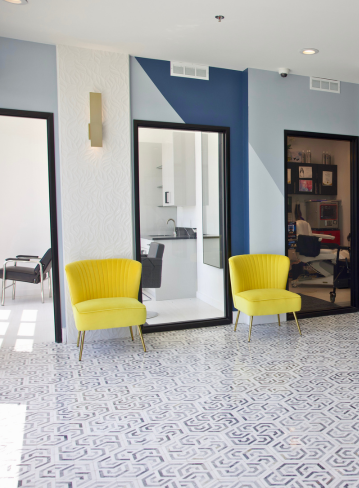 Two yellow chairs on a patterned floor, with glass doors and blue walls in the background