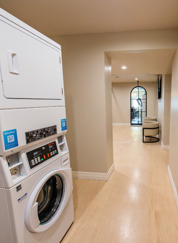 Washer and dryer in a hallway leading to a sitting area with a large window