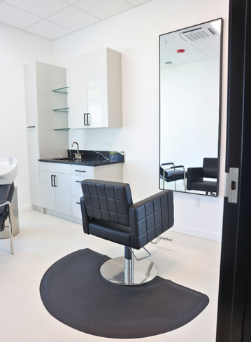 Fully equipped salon suite with hair stylist chair and mirror at Broadway Livonia
