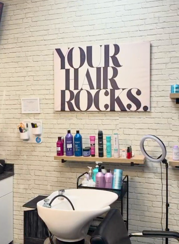 Salon interior with a sign, shelves of hair products, and a wash station