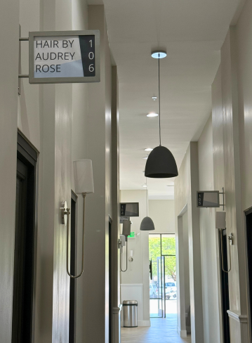 Interior hallway with signs for "Hair by Audrey Rose" and room number 106. Ceiling lights visible