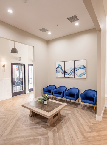 Interior room with two blue chairs, a coffee table, and abstract wall art