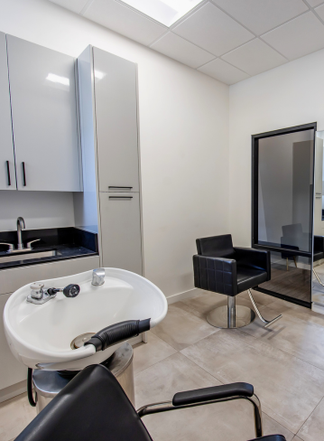 A salon interior with a sink, chair, mirror, and cabinets