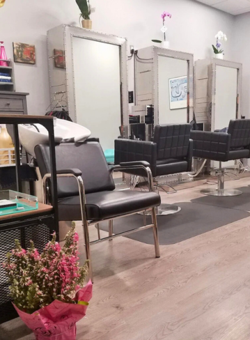 Hair salon interior with mirrors, black chairs, and a bouquet of flowers in the foreground