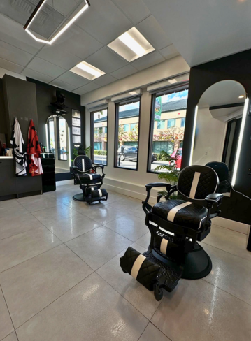 Two barber chairs in a modern salon with large windows and a mirror on the wall