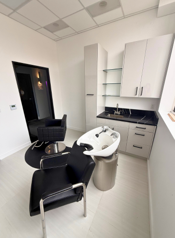 Interior of a hair salon, featuring a shampoo bowl, chair, and storage cabinets