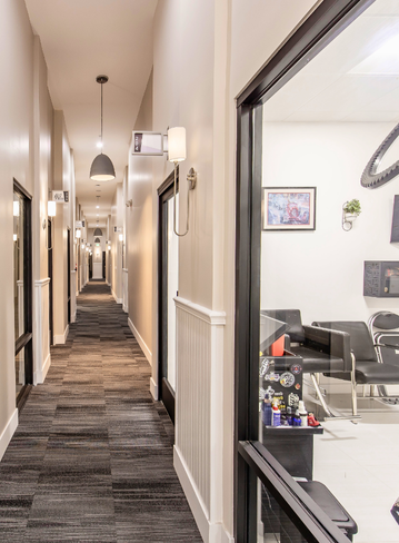 View of a narrow hallway with rooms on either side and soft lighting