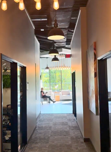 A narrow hallway with hanging lights, leading to a sitting area and large windows