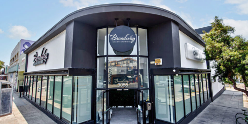 Exterior of a modern building with large windows and a round sign above the entrance