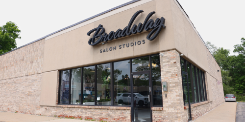 Exterior view of a salon building with large windows and a sign above the entrance