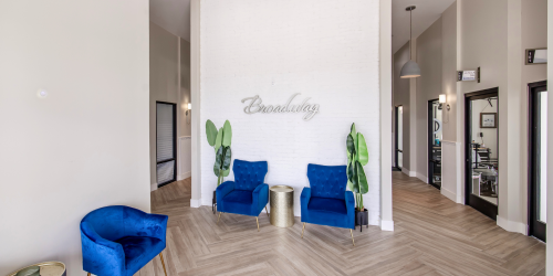 Interior view of a modern waiting area with two blue chairs and plants