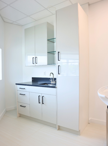 Modern kitchen corner with white cabinets, a black countertop, and a sink