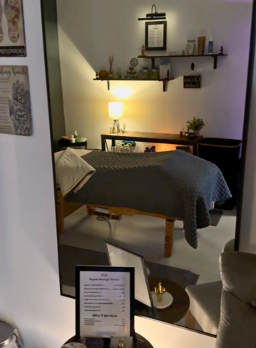 Spa room reflected in a mirror, featuring a massage table and decor