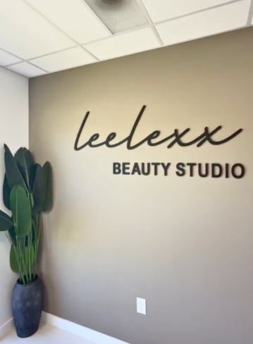 Interior view of a wall with the text "lelexx BEAUTY STUDIO" and a potted plant