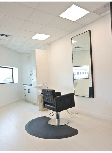 Fully equipped salon suite with hair stylist chair and mirror at Broadway Livonia