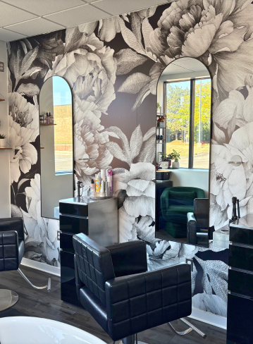 Interior of a salon with floral wallpaper, mirrors, and black chairs