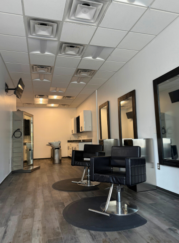 Interior of a salon with three black chairs, mirrors, and light-colored walls