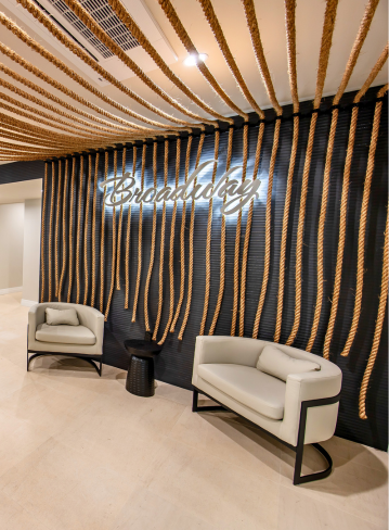 Interior with two white chairs, a black table, and a wall decorated with ropes and the word "Broadwa