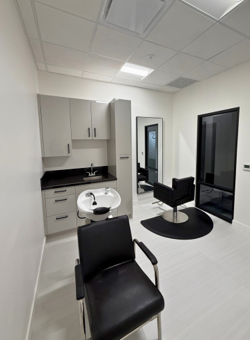 Interior of a salon with chairs, a wash station, and cabinetry against a white wall