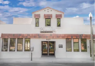 White building with a copper roof, large windows, and a sign above the entrance
