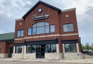 Exterior of a two-story brick building with large windows and a clock on the front