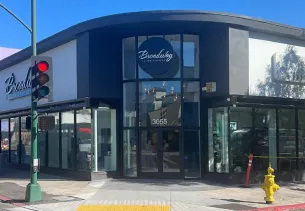 Corner building with large windows and a round sign. Traffic light and fire hydrant visible