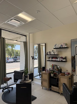 Interior of a salon with two chairs, a mirror, and shelves of hair products