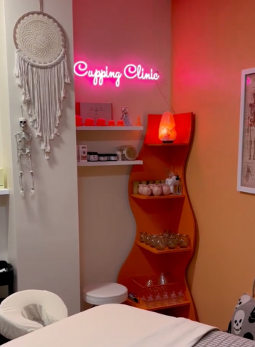 Interior of a treatment room with a "Cupping Clinic" sign and shelves displaying items