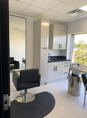 Interior of a salon with a black chair, sink, counter, and a large mirror