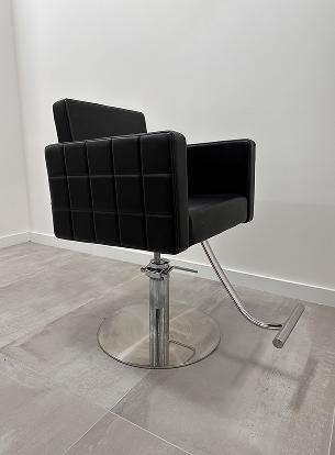Black salon chair with a square pattern, chrome base, and adjustable height