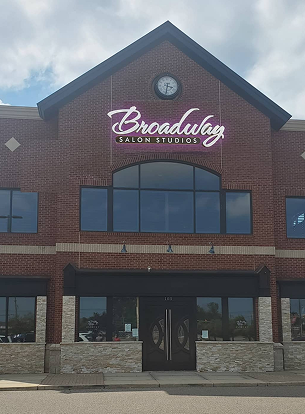 Brick building exterior with large windows and a clock above the entrance