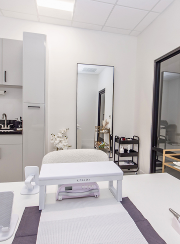 A modern nail salon setup with a work table, mirror, and storage cart