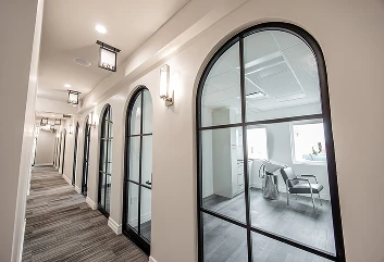 Long hallway with arched glass-paneled doors and overhead lighting
