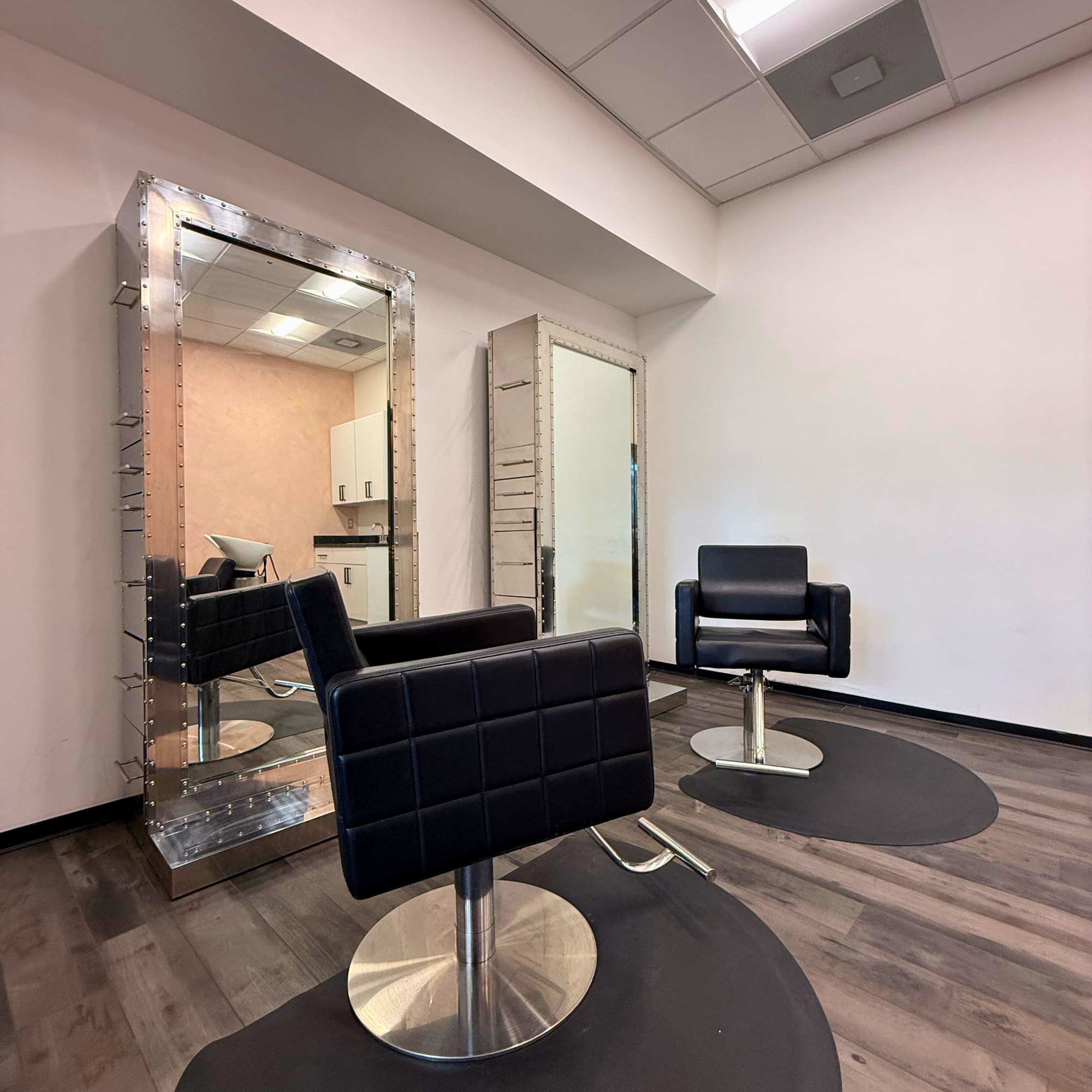 Fully equipped salon suite with hair stylist chair and mirror at Broadway Troy, MI