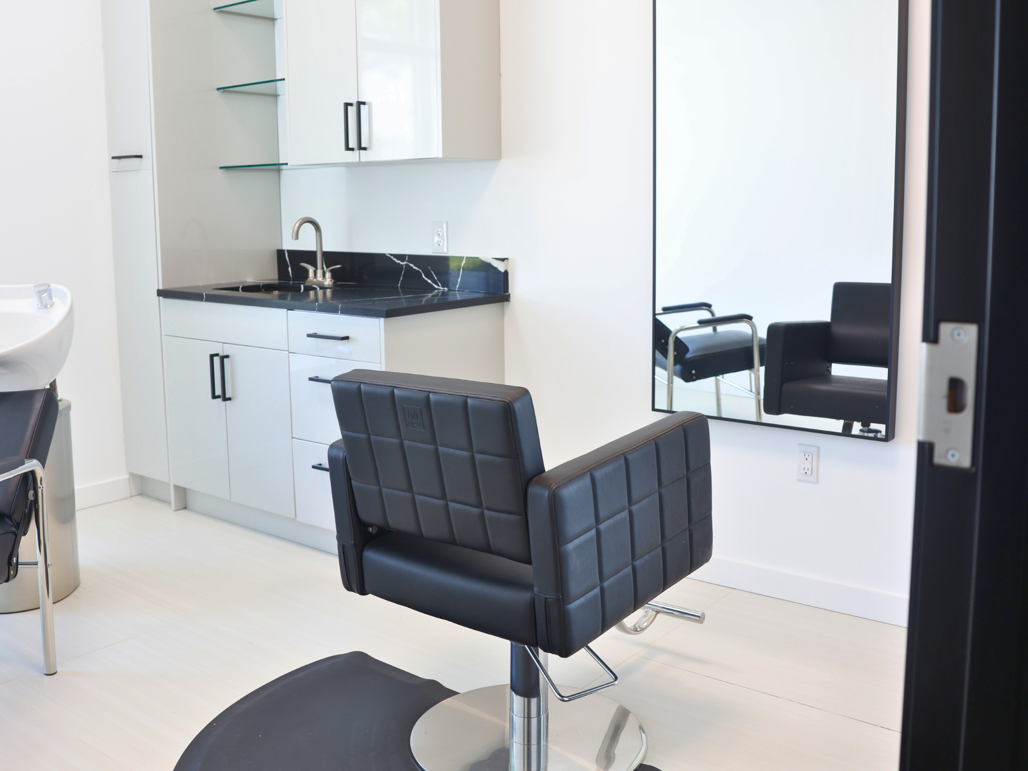 Fully equipped salon suite with hair stylist chair and mirror at Broadway Livonia